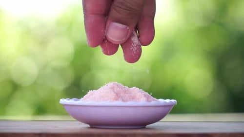 Sprinkling Pink Himalayan Salt on Wooden Surface