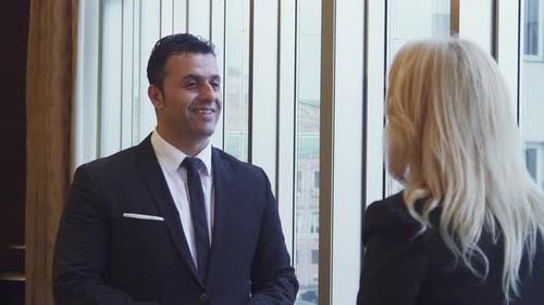 A Friendly Man Shakes His Partner's Hand in a Bright Office