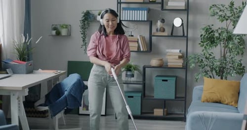 Woman Dances While Cleaning Home Listening to Music