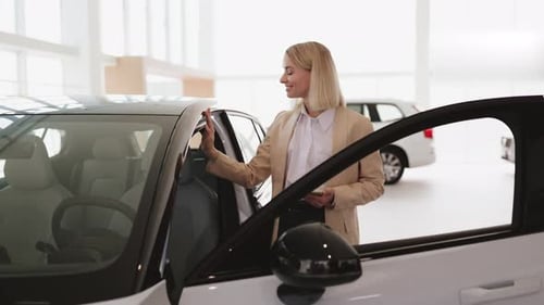 Blond Young Female Choosing Auto Wants to Buy New Automobile in Car Showroom