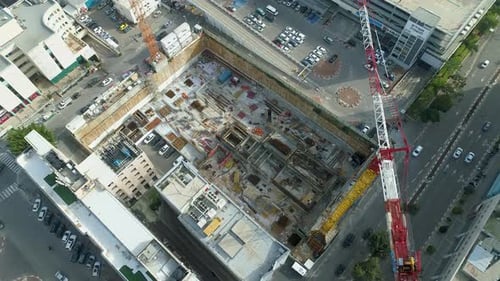 Sitio de construcción elevado para drones con grúa de torre alta a lo largo de una carretera urbana con tráfico.