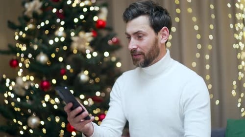 Excited Man Celebrates with Phone at Christmas