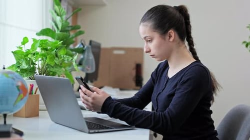 Young Woman Uses Smartphone at Desk