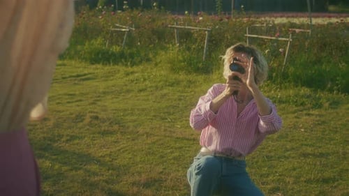 Woman Filming Friend with Vintage Camera in Field