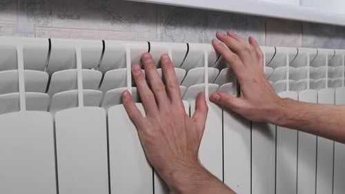Male Hands are Trying to Keep Warm on the Heating Radiator of the House