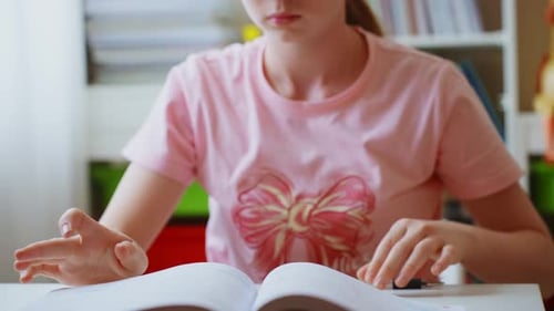 Sad Child with Book Sits at Table