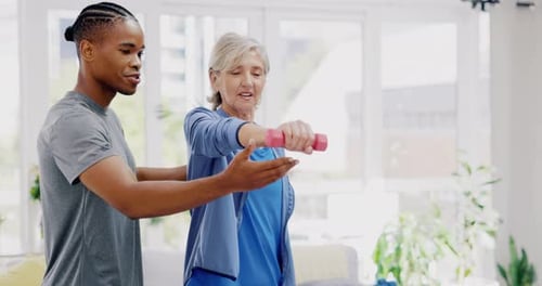 Elderly woman, dumbbells and rehabilitation therapist for exercise in a nursing home