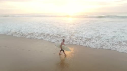Drone of Attractive Surfer Man Walking on Beach with Surfboard