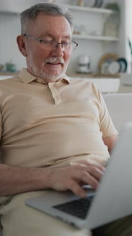 Senior Man Using Laptop Computer on Couch