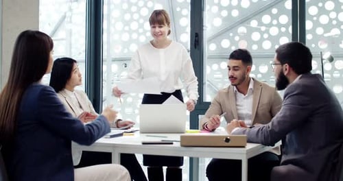 Team Discussing Documents Around Conference Table in Office