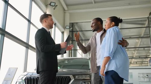 Happy Couple Choosing New Car at Dealership with Consultant