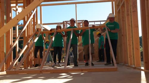 Volunteers lift wall together building habitat for humanity in a community project