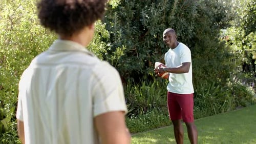 Young Adults Throwing Football in Green Backyard