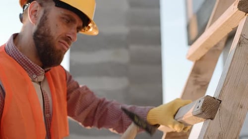 Construction Worker Hammers Wood On Building Site