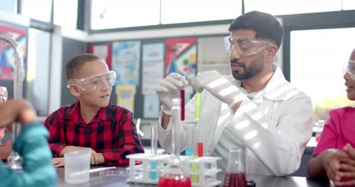 In a school classroom, a biracial teacher demonstrates a chemistry experiment