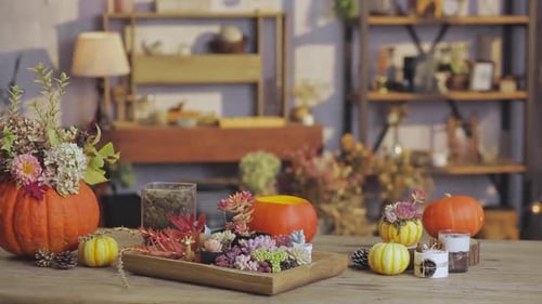 A cozy autumn-themed table arrangement featuring floral pumpkin centerpieces, succulents, candles, a