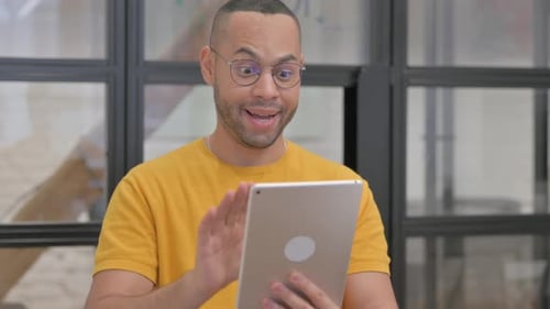 Young Adult Celebrating Success on Tablet in Office