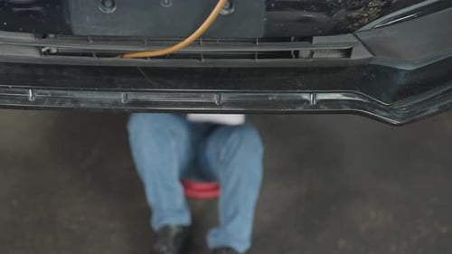 Técnico ou trabalhador de garagem deite-se embaixo do carro e use a lanterna como guia para resolver o problema