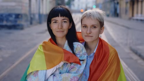 Young Adults Embracing Wrapped in Rainbow Flag