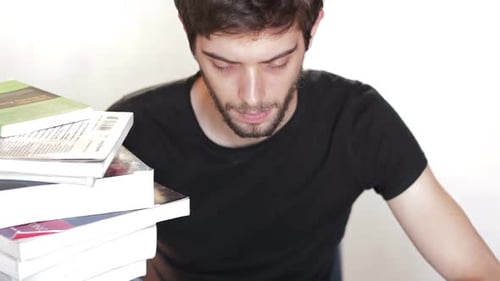 Young Adult Reading on Tablet with Books