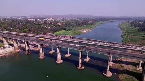 Vehicles are moving on Tilwara Narmada River Bridge with trees and light poles at jotpur, madhya pra