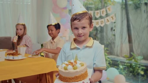 Boy Holds Birthday Cake at Party with Friends