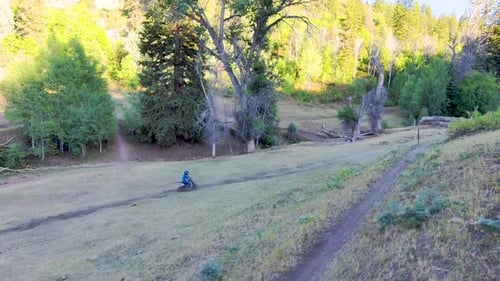 Young motorcycle rider on a dirt bike follows a trail to where his dad is waiting - slow motion