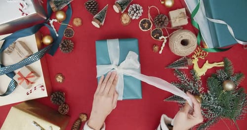 Top view of girl hands unpacking present gift box winter christmas decorations on red background.