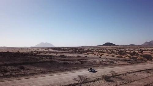 Car Driving on Gravel Road in Aerial Desert
