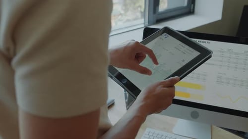 Mains d'un homme examinant un graphique financier sur une tablette numérique au bureau