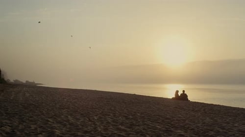 Young Couple Resting on Beach at Sunset. Wide Lovers Dating At