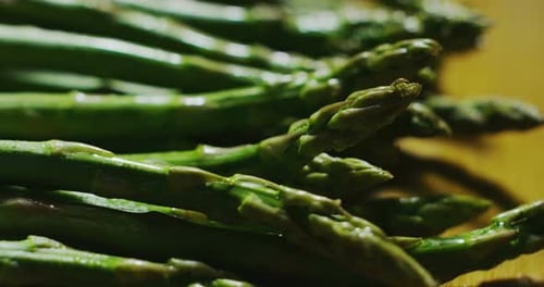 Macro close up slider of fresh juicy asparagus on a wooden kitchen table
