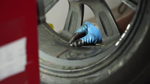 Auto Mechanic Balances Car Tire on Wheel Balancer in Garage Precision Alignment Spin Test Balance