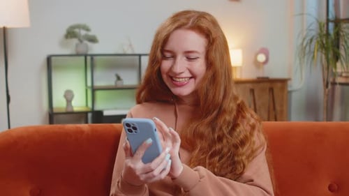 Woman Smiling and Using Mobile Phone on Couch