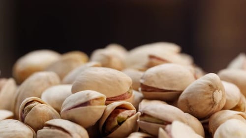 A pile of pistachios on a restaurant table, against a black background