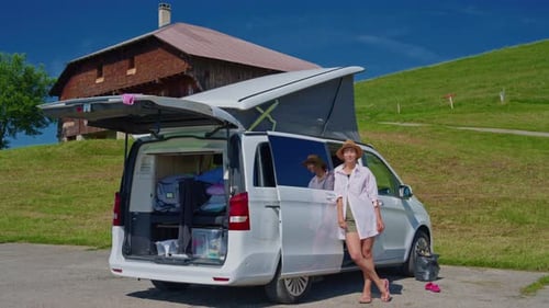 Woman Standing Next to Camper Van in Rural Setting