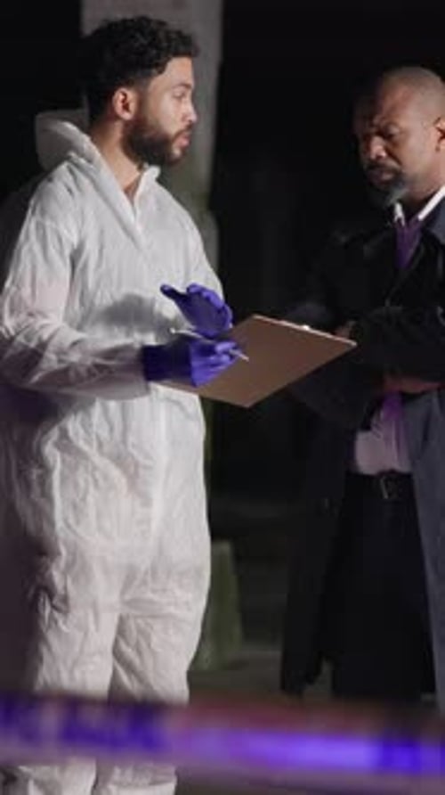 Investigators Confer at Night near Crime Scene Tape