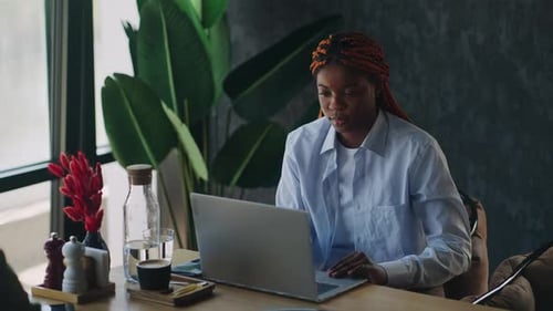 Travail à distance productif Jeune femme de couleur tapant sur son ordinateur portable tout en travaillant sur un projet commercial