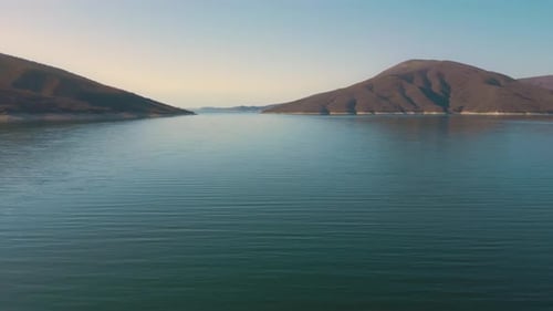 Aerial drone flying over a lake, water dam, with mountains at sunrise. Beautifull dreamy landscape v