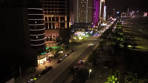 Nighttime Urban Timelapse Revealing Coastal Road Traffic Flow Illuminated Buildings Palm Trees