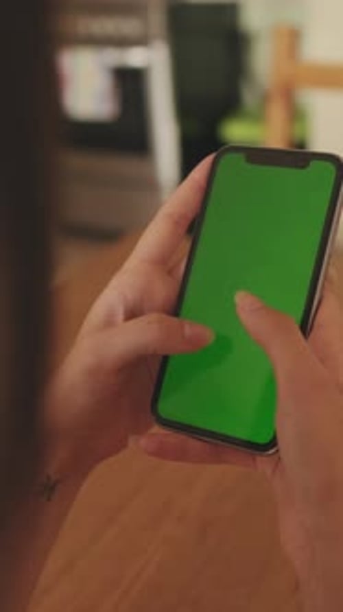 Close-up of young woman's hands using mobile phone green screen chroma key at home