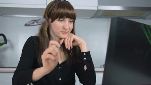 Woman Working on Laptop in Kitchen Holding Glasses