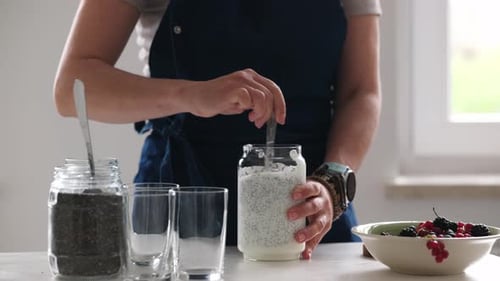 Woman Mixing Homemade Yogurt With Chia Seeds In Glass Bowl
