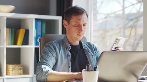 Junger männlicher Unternehmer arbeitet im Home-Office am Computerarbeitsplatz eines Freiberuflers oder Studenten