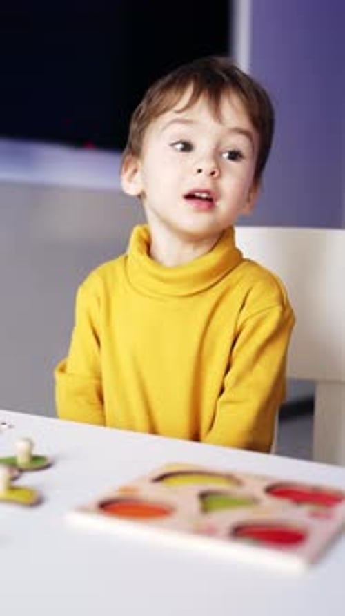 Cute smart little boy sitting at the desk. Teenage kid taking two pieces