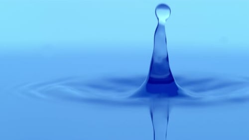 Water droplets falling on blue water surface in slow motion