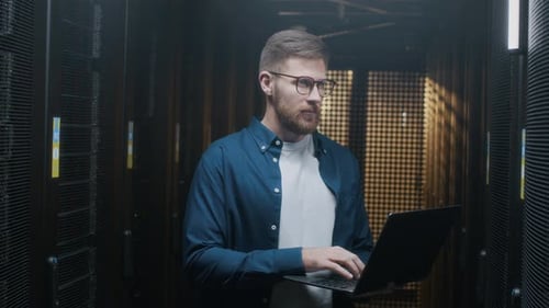 Adult Works on Laptop in Server Room