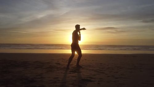 Man Silhouette Practicing Martial Arts on Beach at Sunset