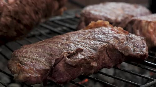 Saftiges Steak, das auf dem Grill über offener Flamme brutzelt