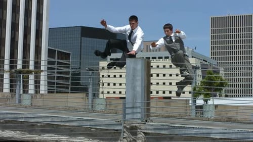Men do parkour moves on rooftop in city